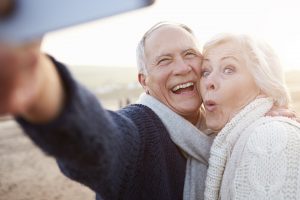 A pair of mature adults, smiling, carefree about their implant-supported dentures.