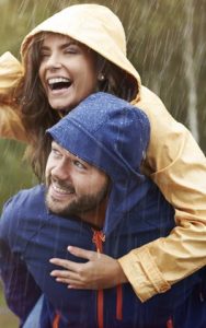 A young couple wearing rain coats outside, enjoying healthy gums.