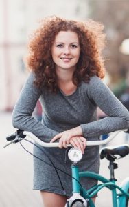 A young woman leaning forward on the handlebars of a bike.
