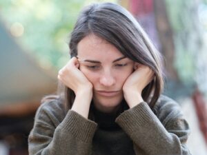 Woman rests her face on her hands in a show of discomfort